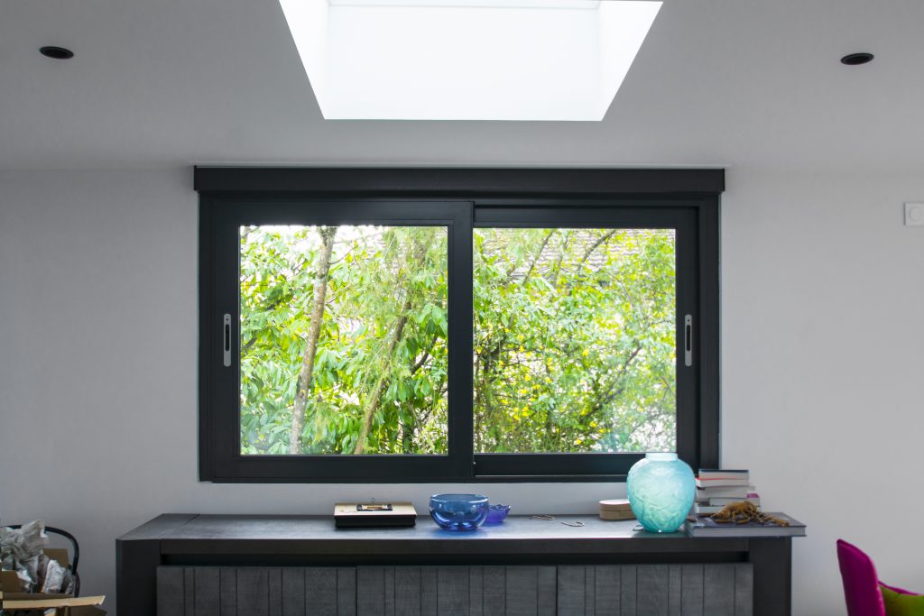 Fenêtre coulissante anthracite à deux vantaux dans un intérieur lumineux
